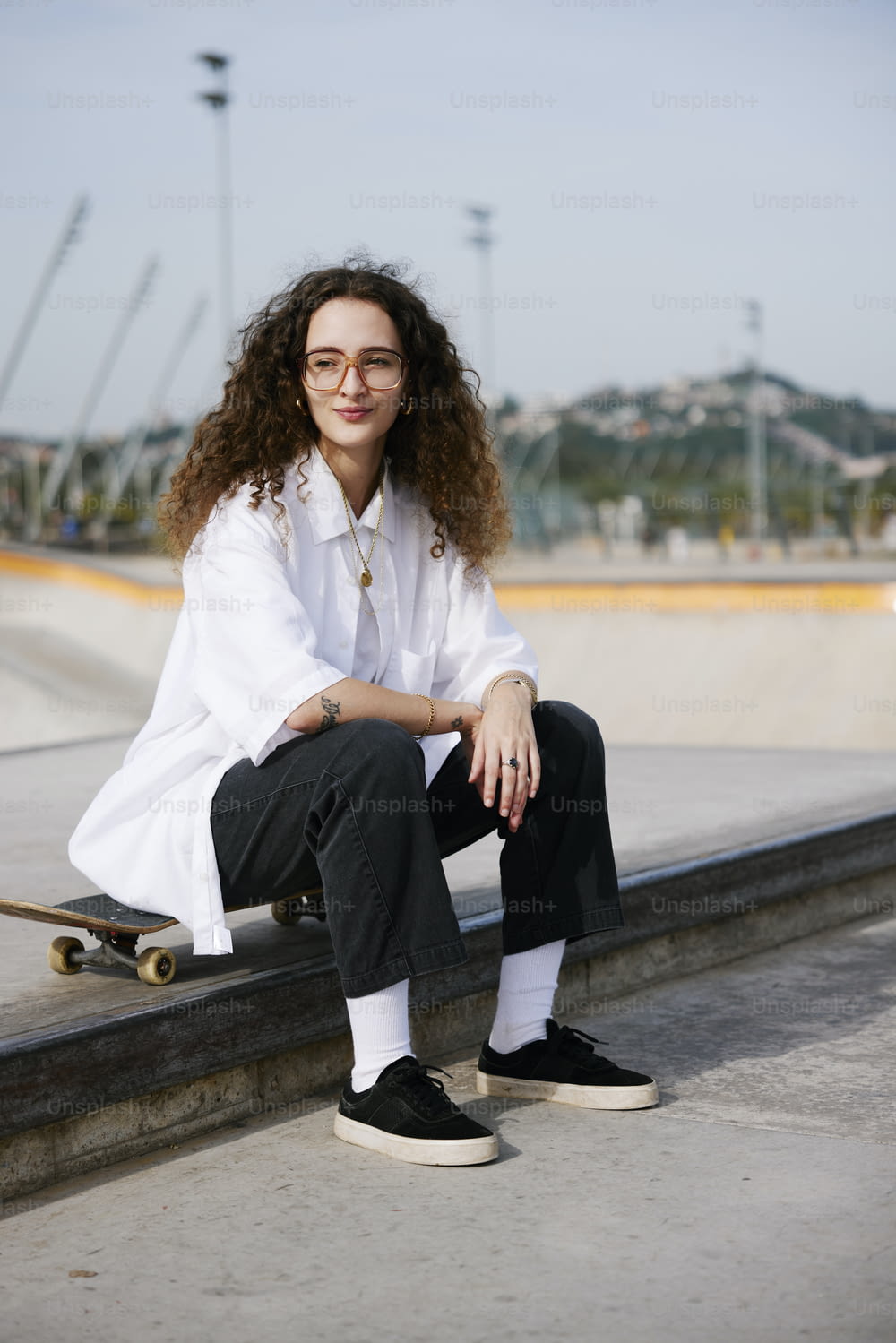 Una donna seduta su una sporgenza con uno skateboard