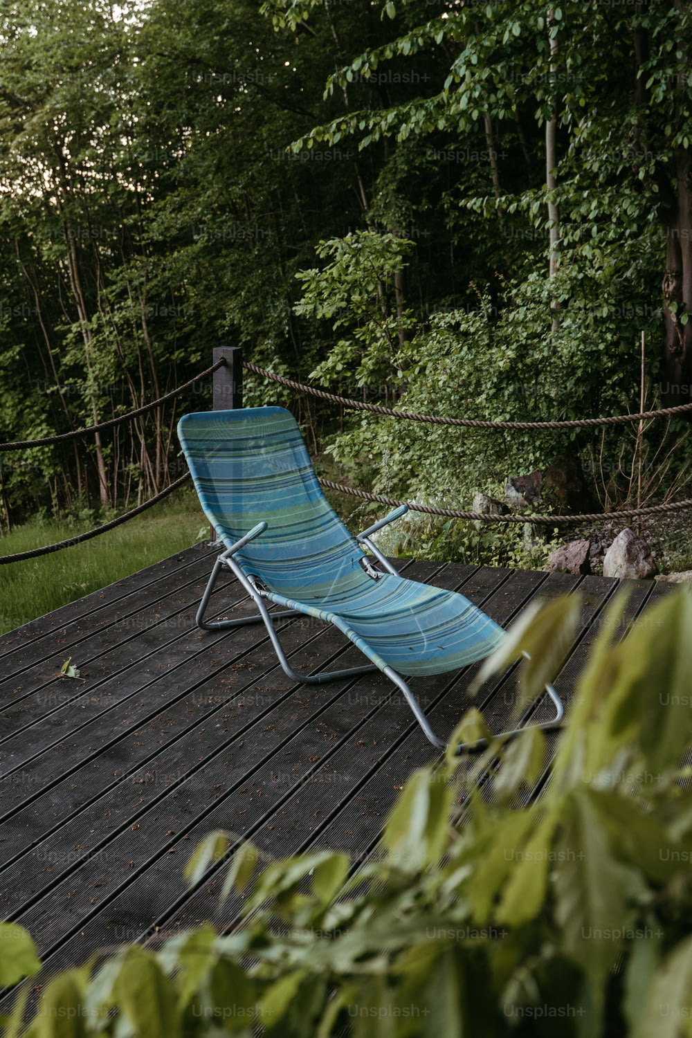 una sedia da giardino blu seduta in cima a un ponte di legno