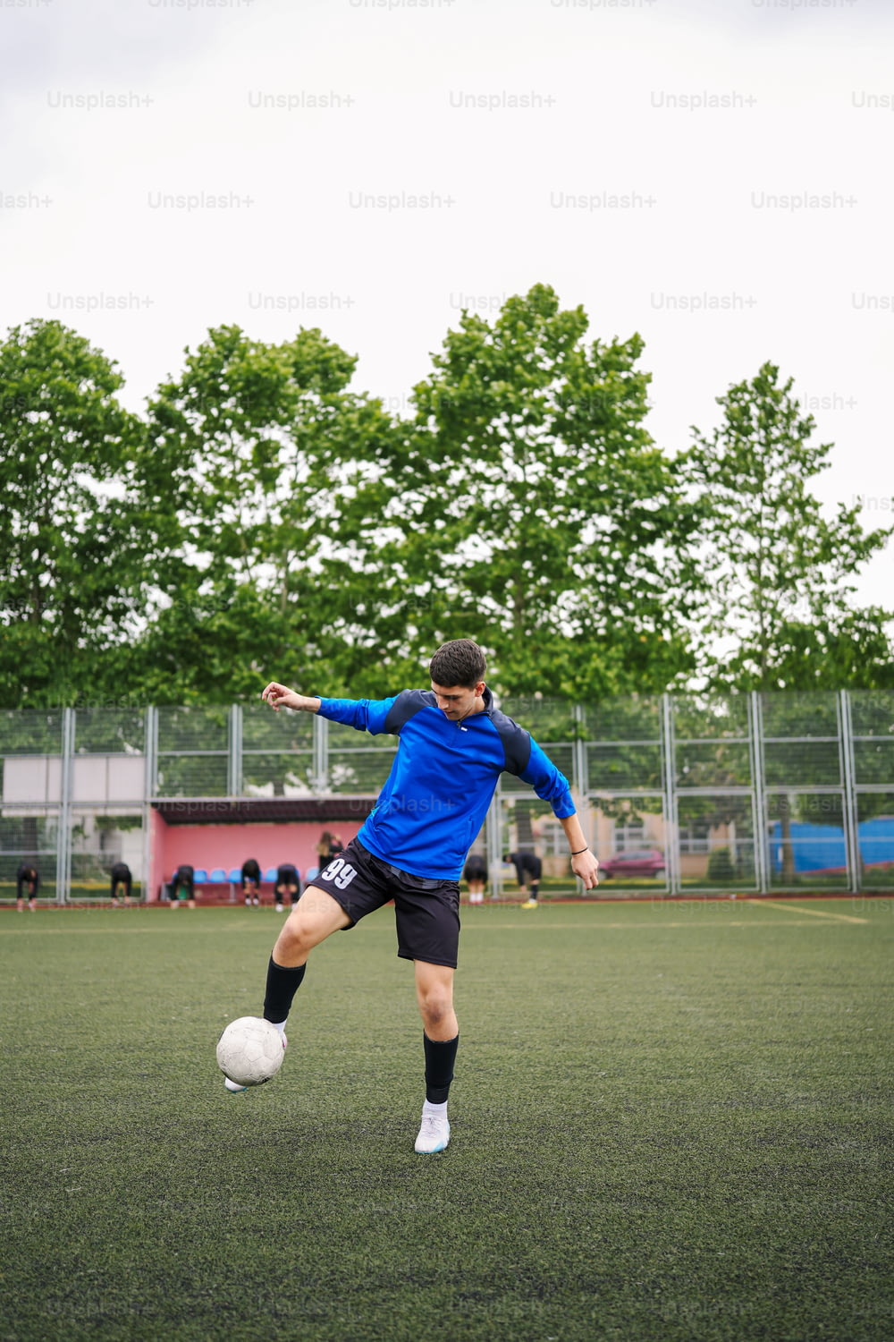 um jovem chutando uma bola de futebol em um campo