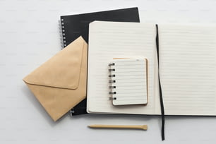 un cuaderno, un bolígrafo y un sobre sobre una mesa