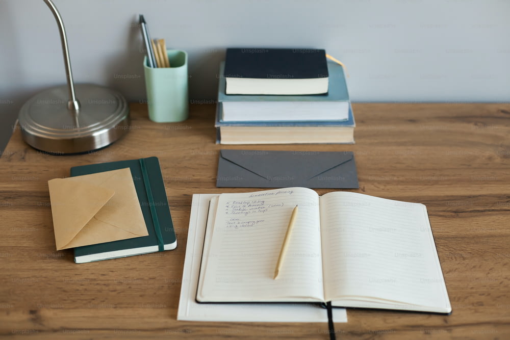 ein Holztisch mit Notizbüchern und einer Lampe