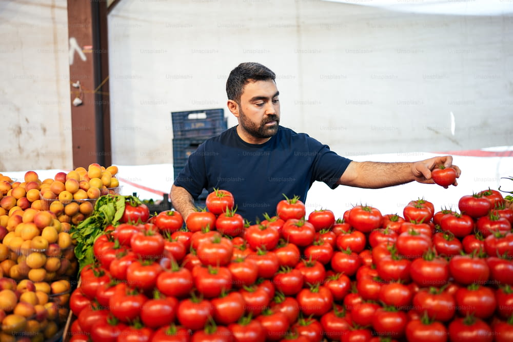Ein Mann, der vor einem Haufen Tomaten steht