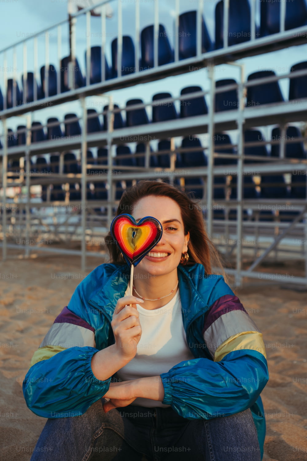 Una donna che tiene un lecca-lecca a forma di cuore davanti a uno stadio
