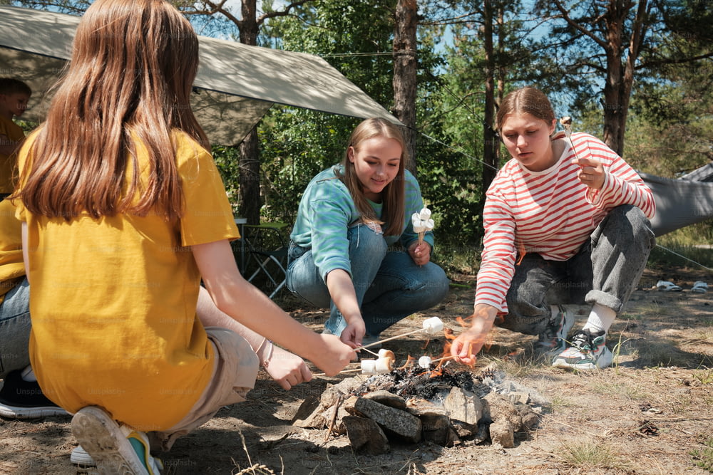a group of young women sitting around a campfire