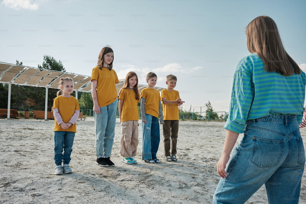 Un grupo de niños parados en la cima de una playa de arena