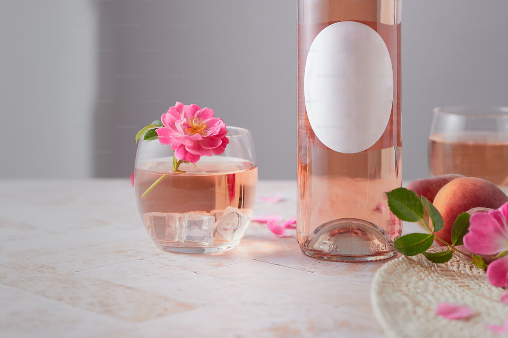 a glass of rose wine next to a bottle of wine