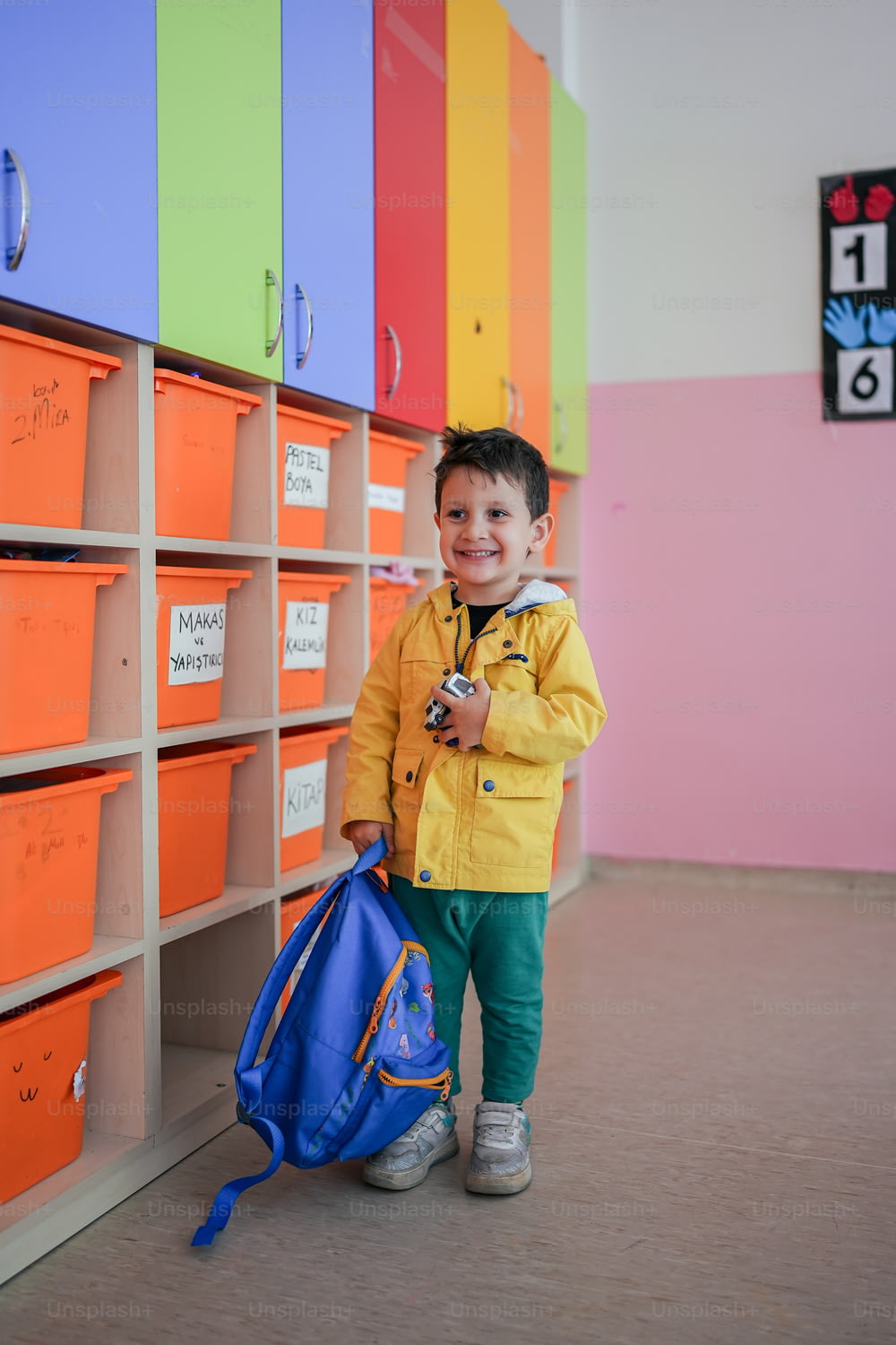 a young boy standing in front of a wall of lockers