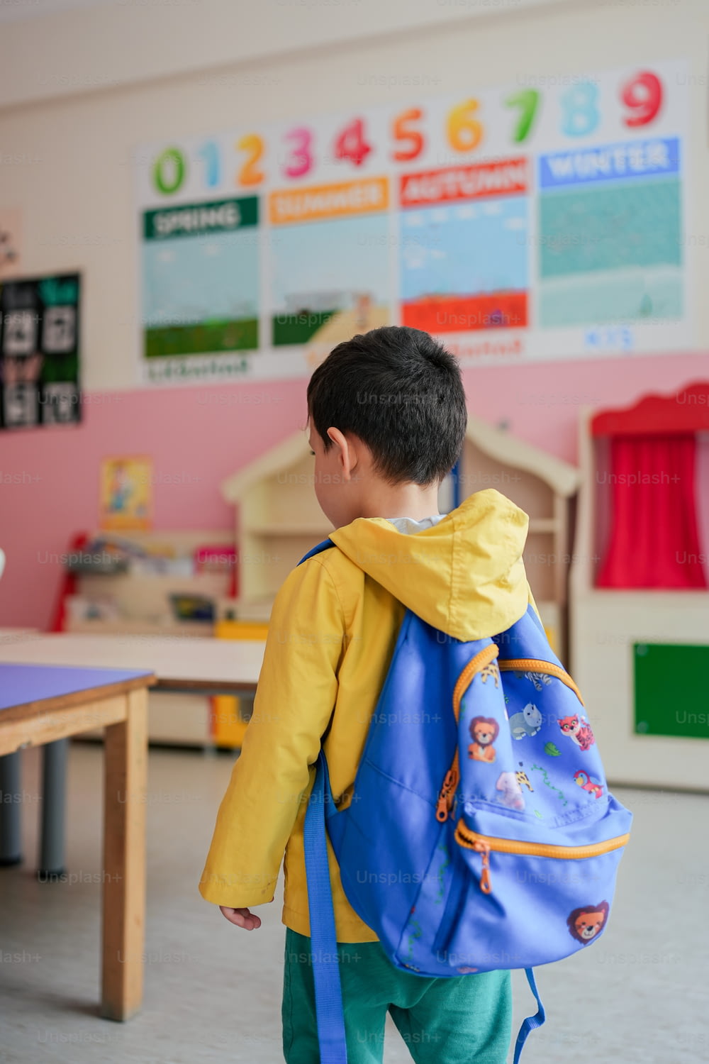 a young boy with a blue backpack in a classroom