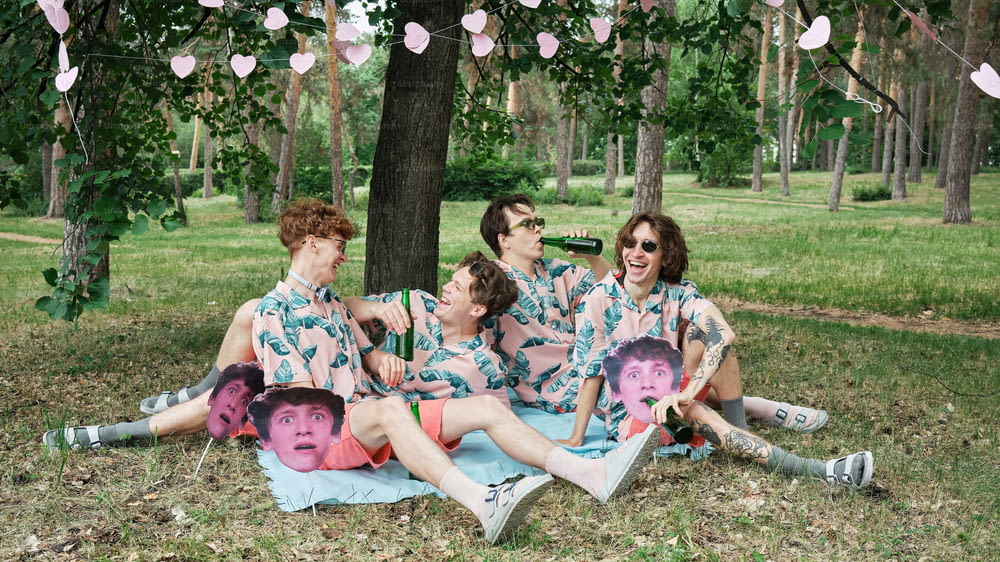 a group of people sitting on top of a blanket under a tree