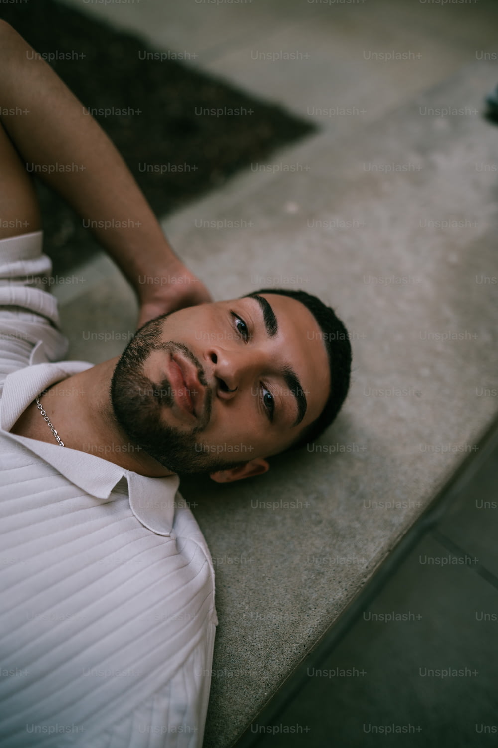 a man laying on the ground wearing a white shirt