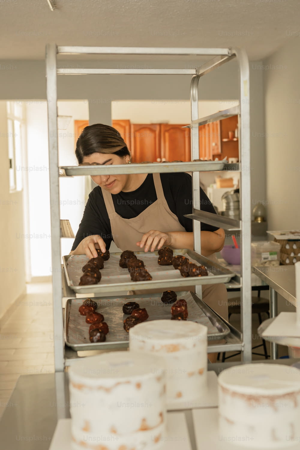 a woman in a kitchen making donuts on a rack