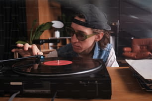 um homem de chapéu e óculos tocando um disco