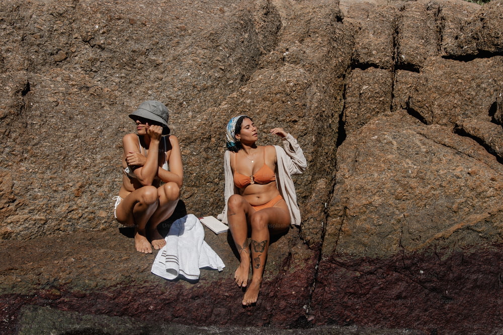 a couple of women sitting next to each other on a beach