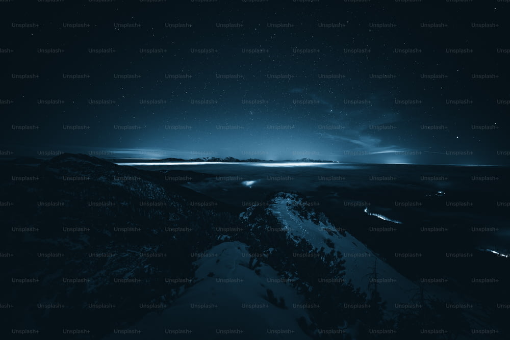 the night sky is lit up over a snowy mountain