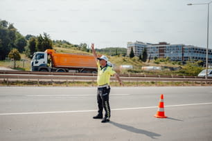 um homem parado à beira de uma estrada ao lado de um cone de trânsito