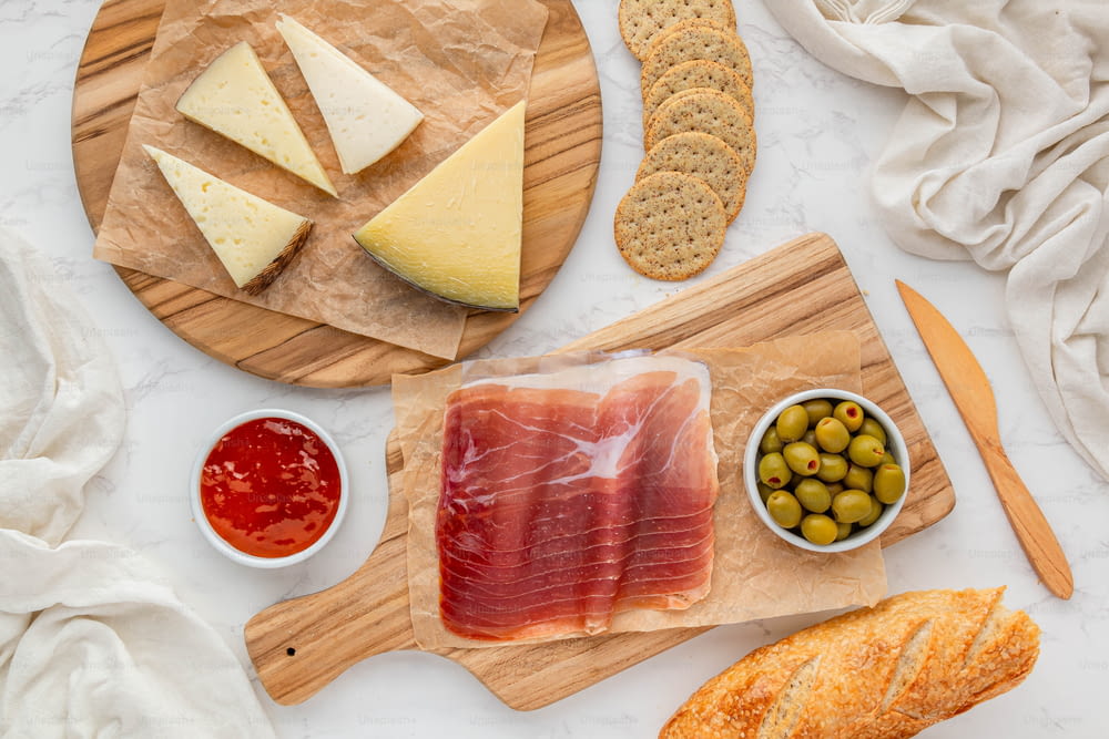 a variety of cheeses, crackers, olives, and meats on