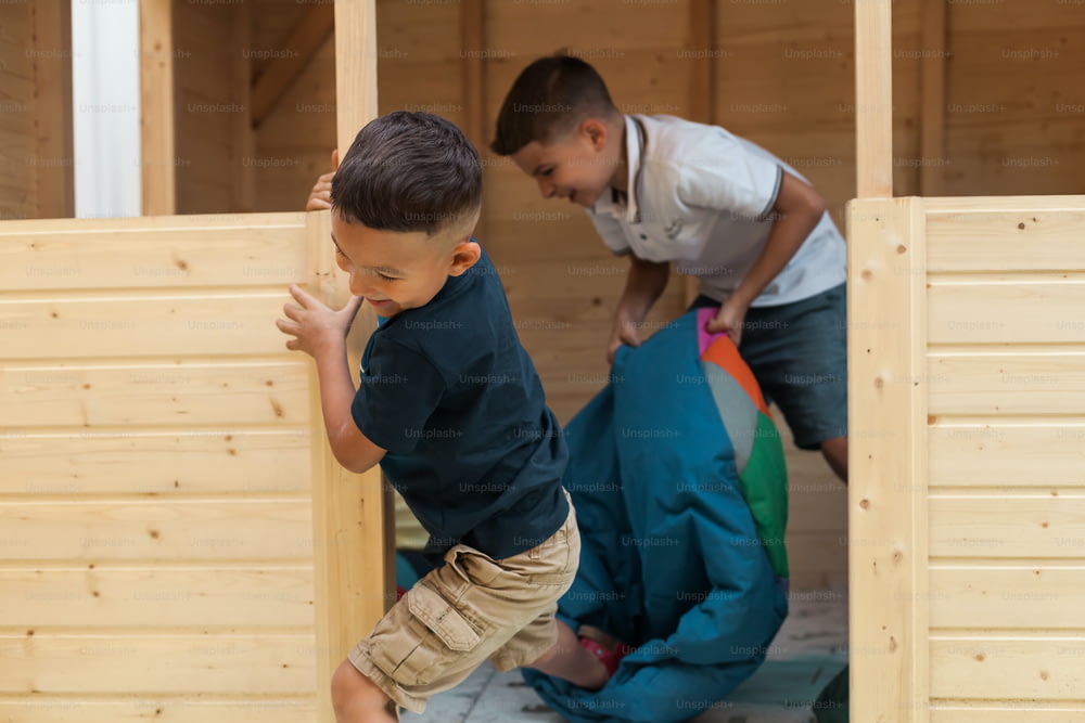 two young boys playing in a wooden structure