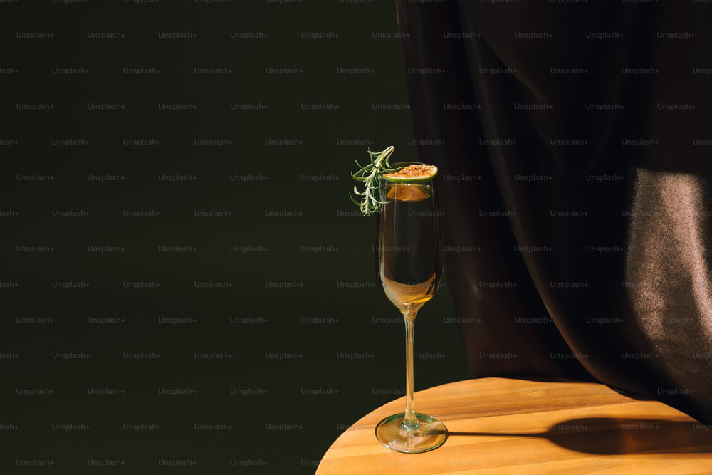 a glass of champagne with a sprig of rosemary on top