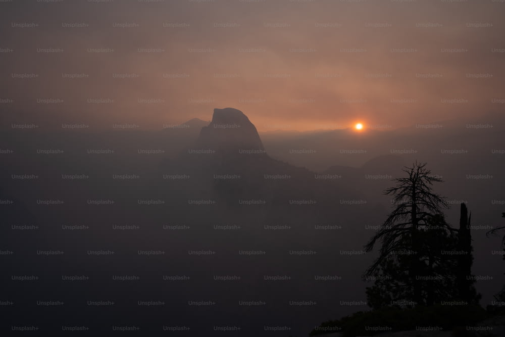 Il sole tramonta sulle montagne nella nebbia
