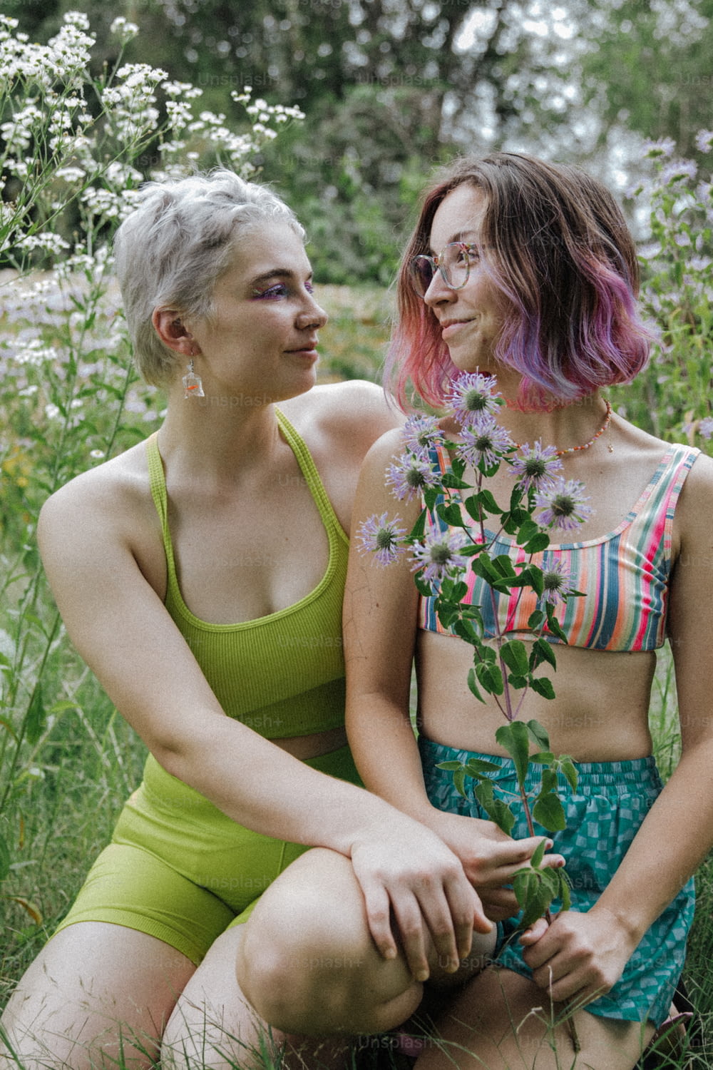 two women sitting in a field of flowers