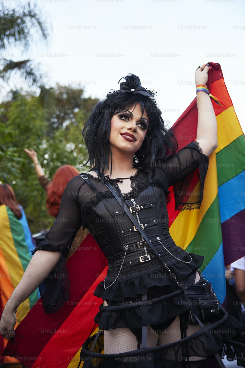 uma mulher em um espartilho segurando uma bandeira do arco-íris