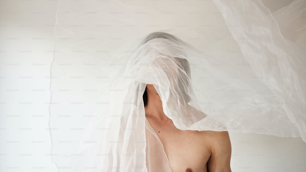 a shirtless man with a white veil over his head
