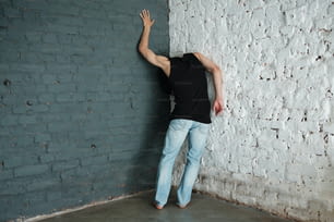 Un homme appuyé contre un mur de briques blanches
