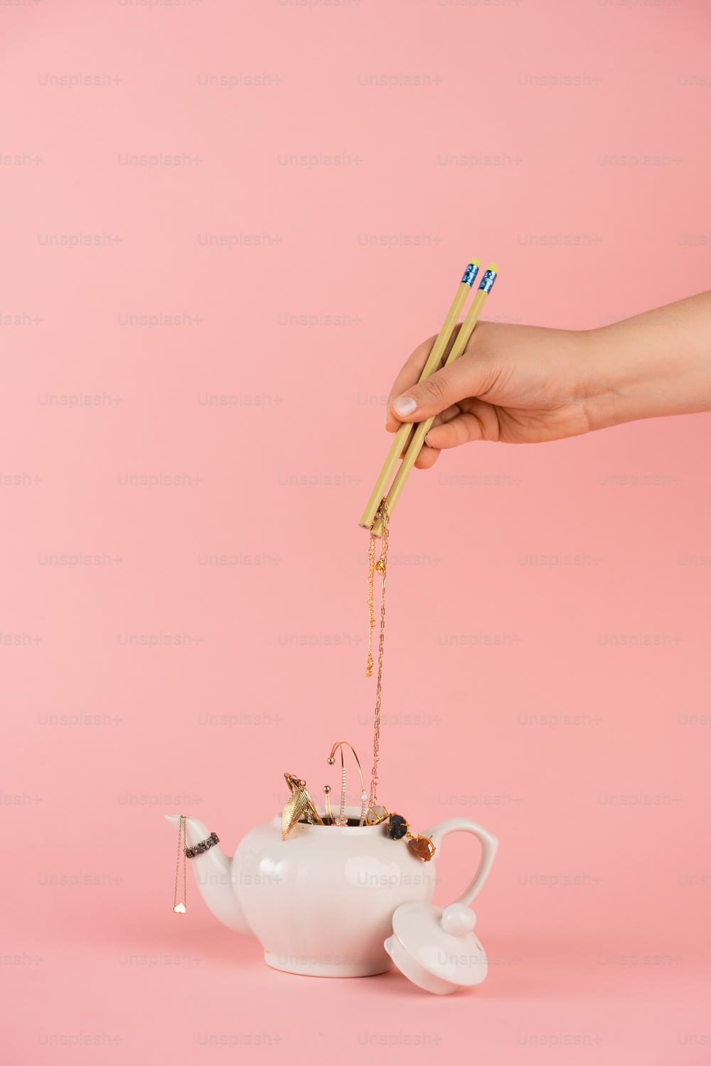 a person holding a pair of chopsticks over a teapot