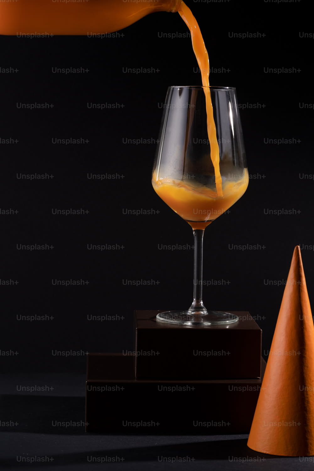 a person pouring orange juice into a wine glass