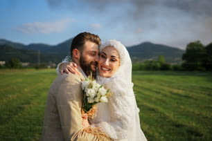 Una sposa e uno sposo che si abbracciano in un campo
