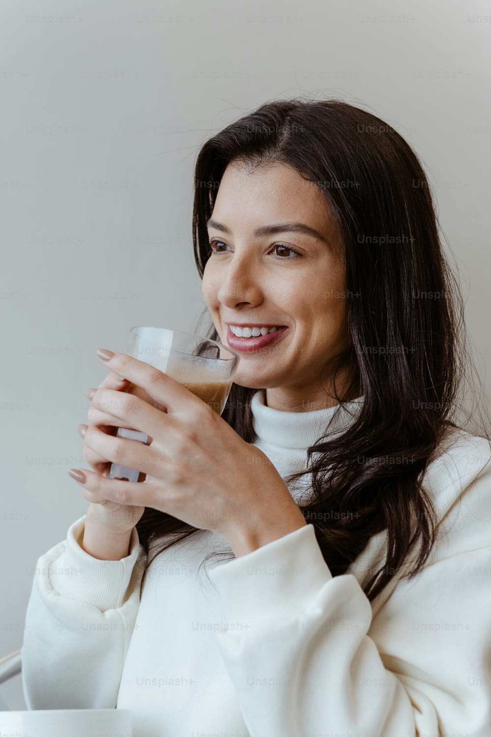 a smiling woman holding a glass of coffee