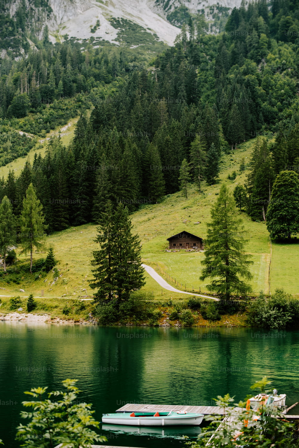 a boat sitting on top of a lake next to a lush green hillside