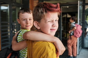 two young boys hugging each other outside a building