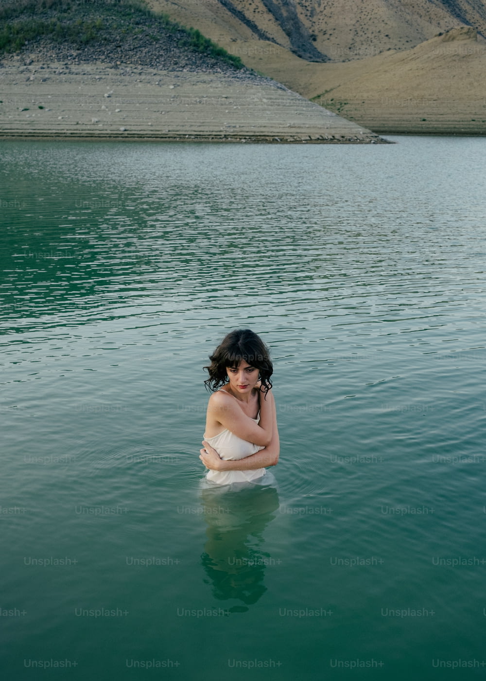 a woman in a white dress sitting in a body of water