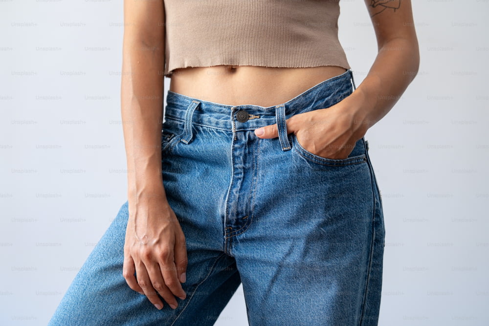 a woman wearing a tan crop top and blue jeans