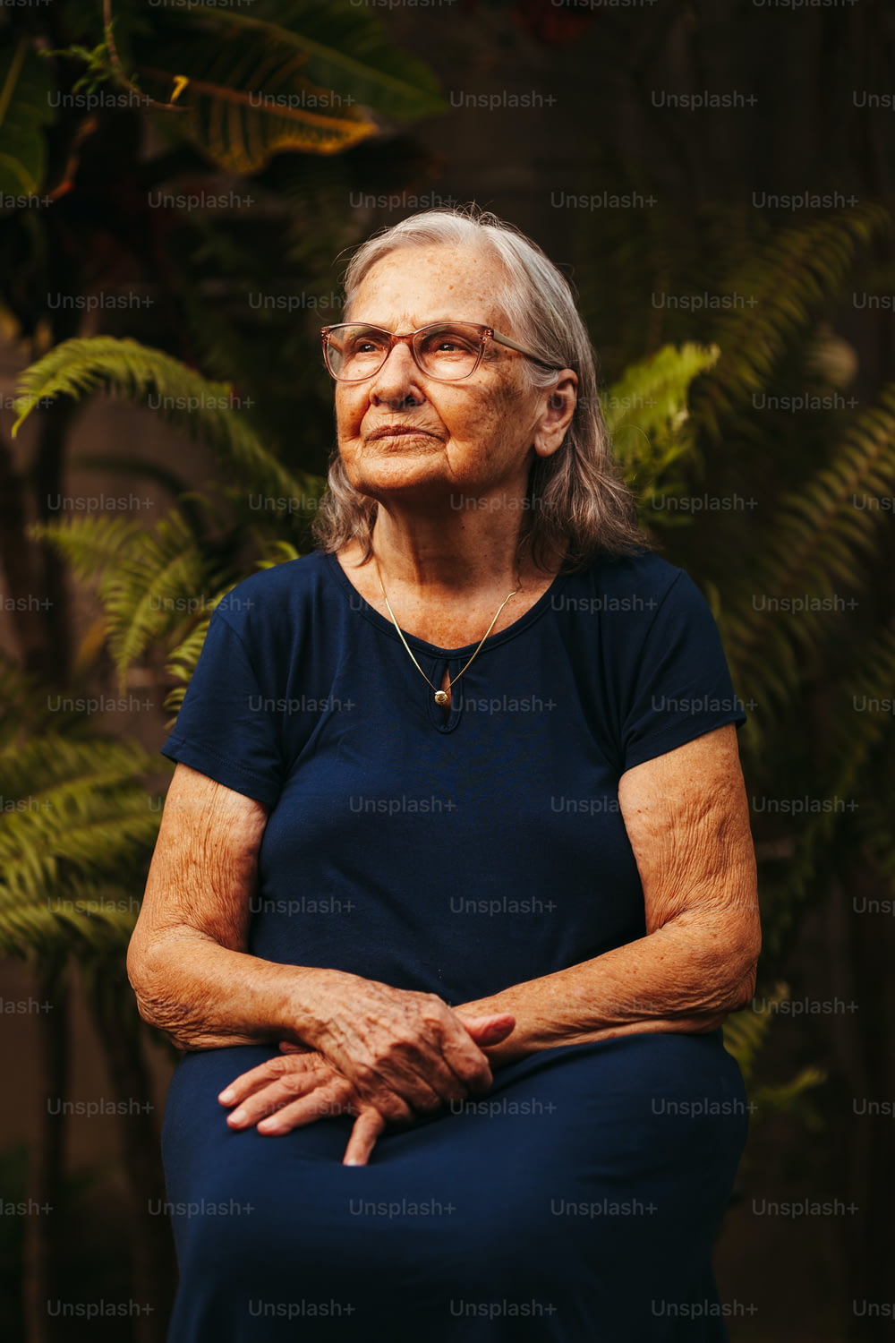 an older woman sitting in front of a tree