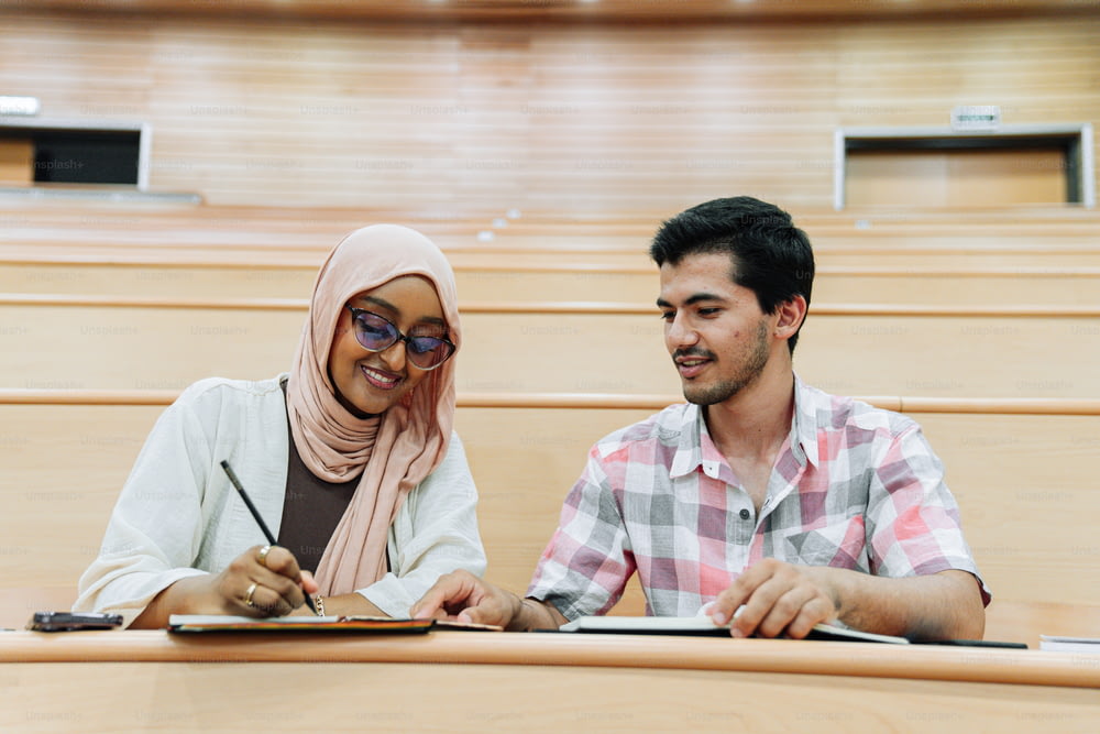 a man and a woman sitting at a table in a lecture hall
