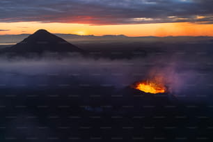 Un volcán hace erupción de lava cuando el sol se pone