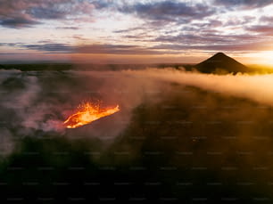 a volcano spewing out lava at sunset