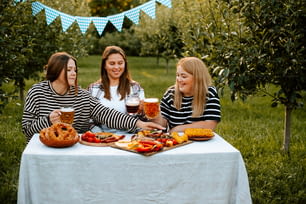 a group of women sitting around a table with food and drinks