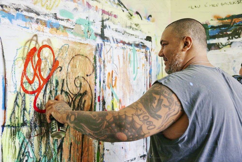 Ein Mann, der auf eine mit Graffiti bedeckte Wand schreibt