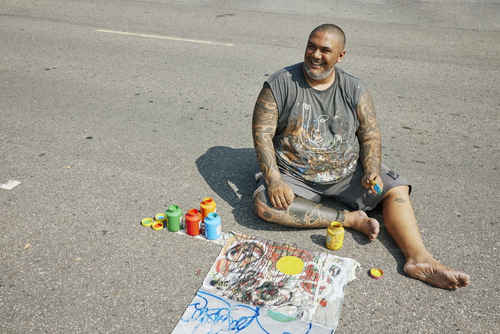 a man sitting on the ground next to a painting