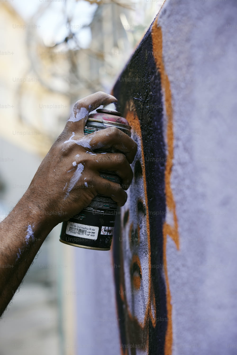a person spray painting a wall with orange and black paint