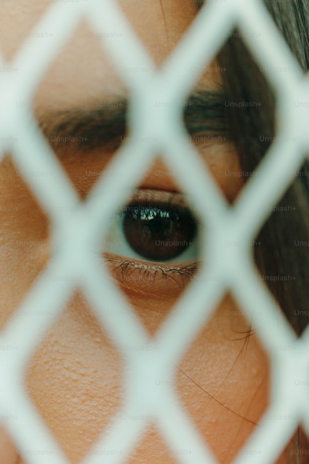 a close up of a person's eye through a chain link fence