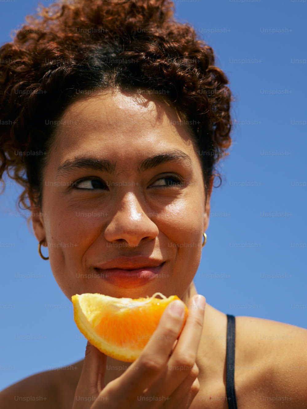 a woman holding an orange slice in her hand