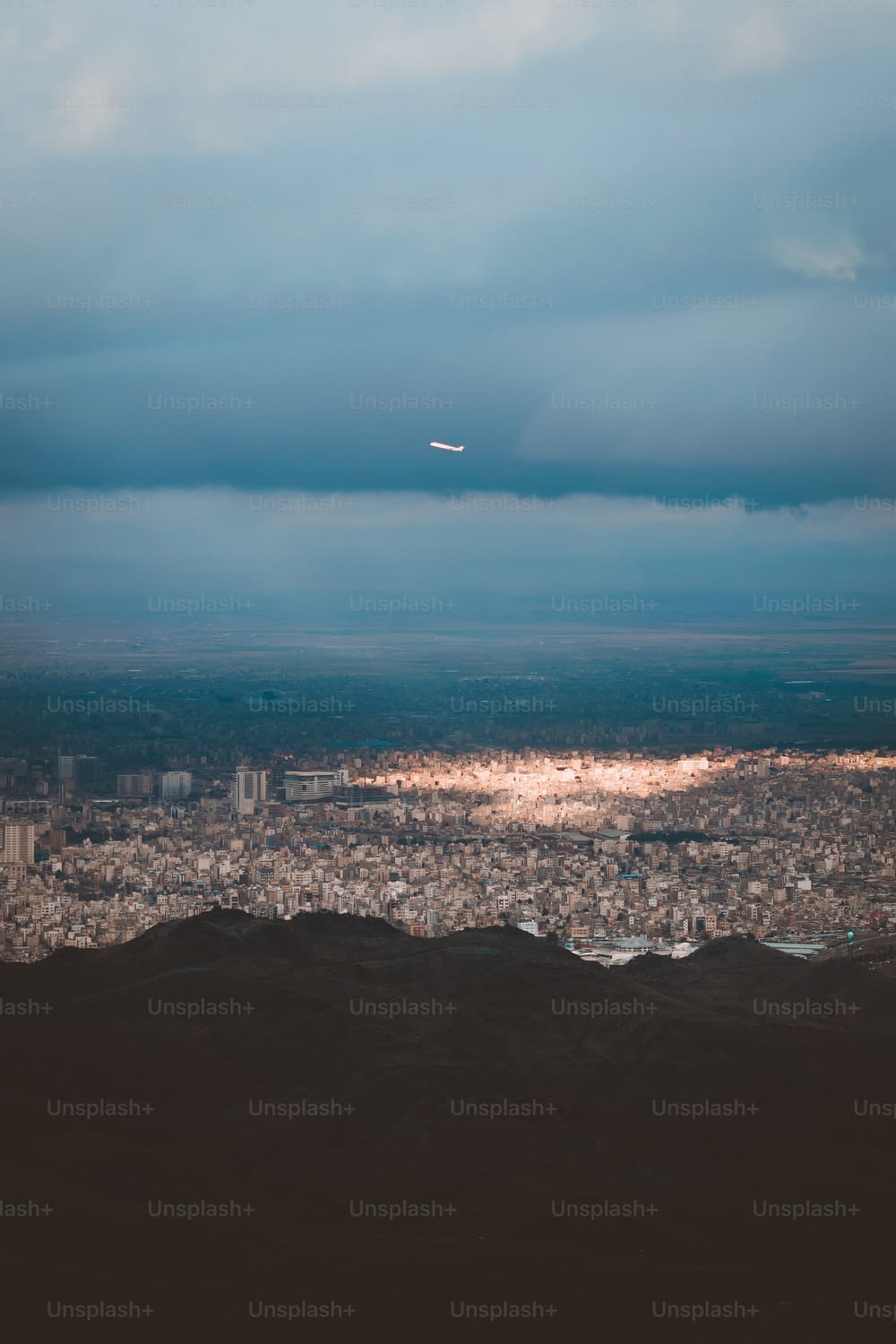 an airplane flying over a city under a cloudy sky