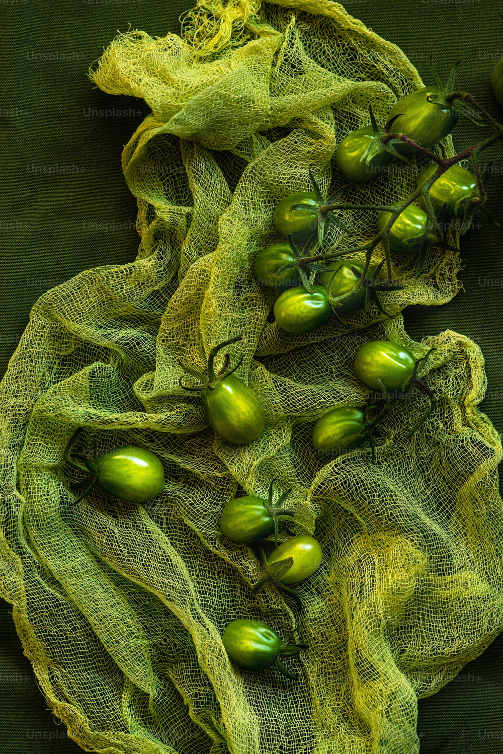 ein Bündel grüner Tomaten, die auf einem grünen Tuch sitzen