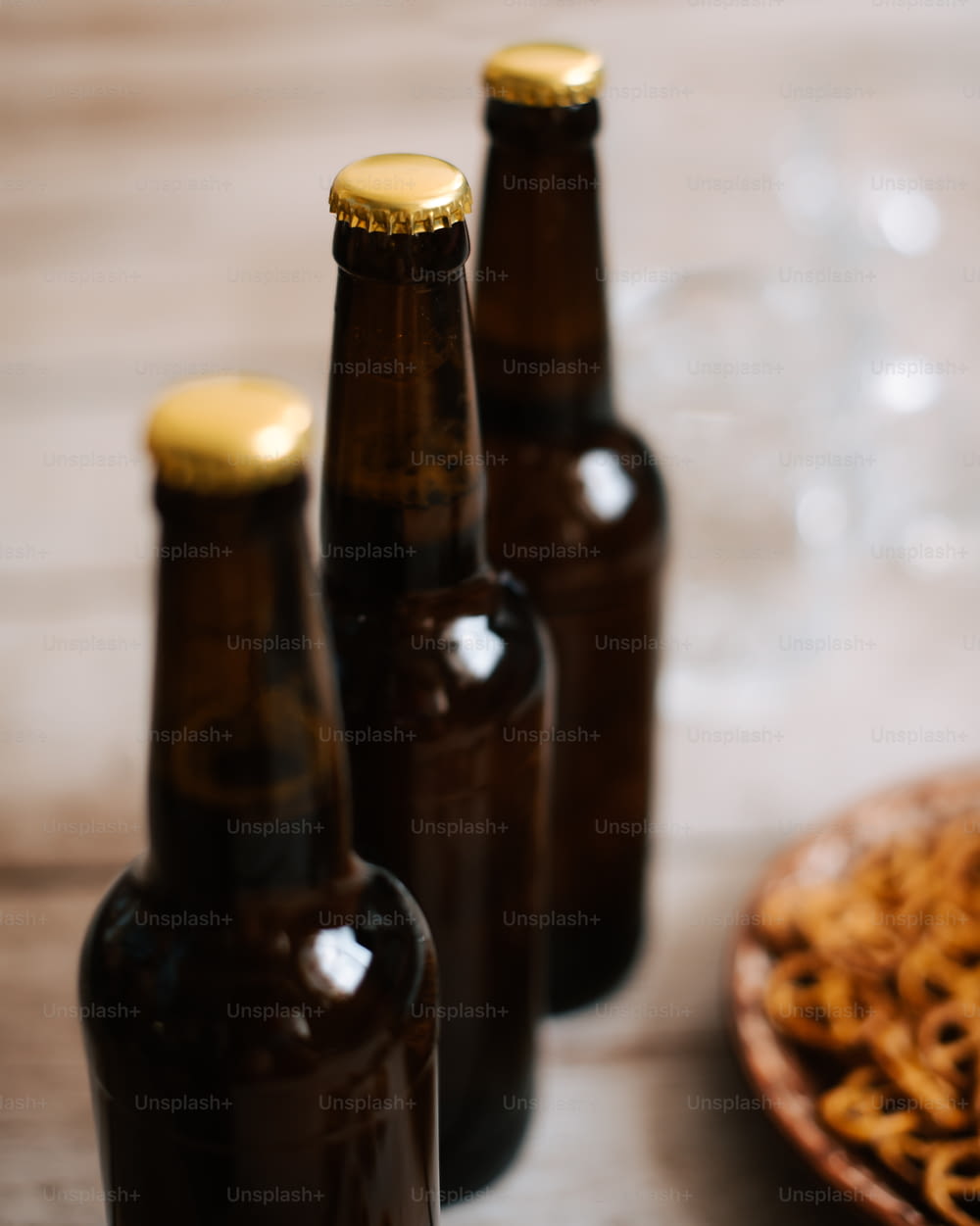 three brown beer bottles sitting next to a plate of pretzels