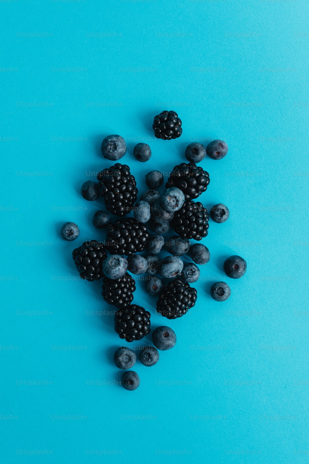 a pile of berries and blueberries on a blue background