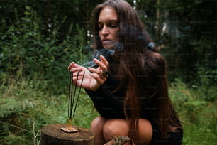 a woman sitting on a stump smoking a cigarette